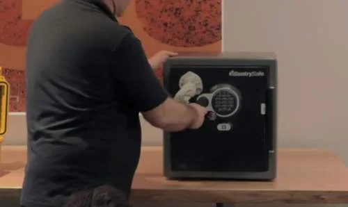 Abertura de cofre CountrySafe digital: pessoa manipula fechadura com objeto, tema ímãs de neodímio.