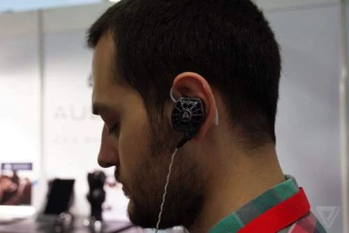 Fones de ouvido magnéticos planos Audeze, modelo in-ear, sendo usados no ouvido direito de um homem. Design detalhado.