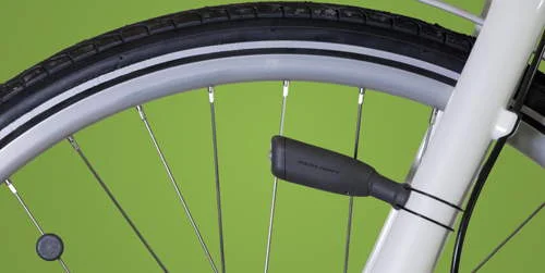 Luz e ímã para bicicleta. Sensor preto preso ao quadro branco, ímã redondo no raio da roda.