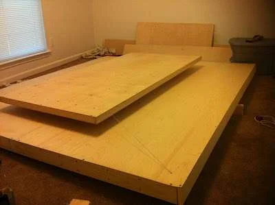 Cama flutuante magnética 3: estrutura de cama em madeira clara com base retangular e painel superior suspenso, criando efeito de levitação.