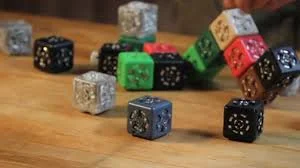 Cubelets, robôs modulares. Cubos coloridos em preto, cinza, verde e vermelho, empilhados e espalhados sobre uma mesa de madeira.