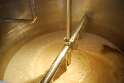 Cerveja em fermentação, agitada em tanque de inox. Etapa vital para influenciar o sabor da cerveja.
