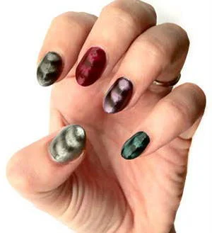 Esmaltes magnéticos em unhas de mão, com padrões e cores variados: cinza listrado, vinho, roxo e verde escuro.