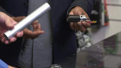 Tubo cilíndrico de metal e motor compacto com fios, itens relacionados a fraude no ciclismo com imãs escondidos.