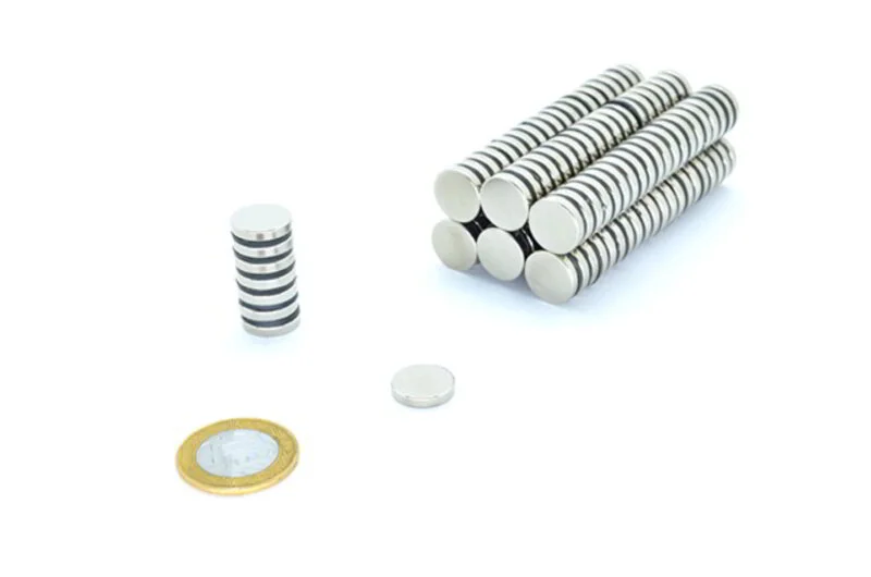 Ímãs de neodímio 15x3mm, discos prateados: uma pilha, um solto e seis pilhas lado a lado, com moeda de R$1 para escala.