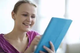 iPad com smart cover azul, sendo usado por mulher loira sorridente.