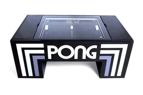 Mesa de centro preta retangular com jogo Pong embutido. Tela acesa exibindo o jogo, placar, e logo PONG em branco nas laterais.