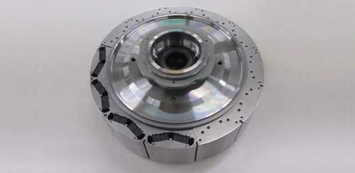 Motor elétrico Honda sustentável com ímãs de neodímio: peça circular metálica, prateada, com segmentos pretos visíveis na borda.