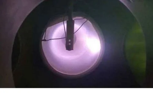 Ímã suspenso no centro de uma câmara de plasma, com intensa luz roxa e fios. Experimento de ímã em plasma.