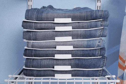 Organizadores para armários: 8 calças jeans dobradas em separadores brancos empilhados sobre prateleira de arame.