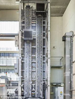 Primeiro elevador que se move para os lados com magnetismo: cabine escura em movimento vertical dentro de uma estrutura metálica de múltiplos eixos.