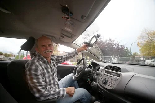 Quebra sol para carros com imãs, escuro e compacto, ajustado no para-brisa por um homem sorridente.