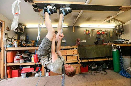 Sapatos Magnéticos, nova criação de Colin Furze: homem pendurado de cabeça para baixo no teto da oficina.