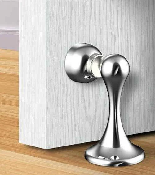 Trava portas magnético prateado, design moderno, conectado a uma porta de madeira clara sobre piso de madeira.