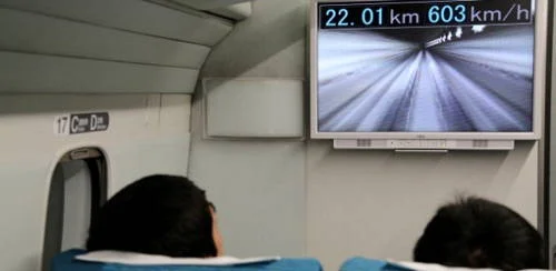 Trem magnético japonês. Monitor interno mostra 603 km/h, seu novo recorde de velocidade. Passageiros.