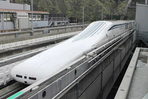 Trem magnético japonês branco e aerodinâmico com nariz longo, em trilho elevado. Bateu recorde de velocidade 603 km/h.