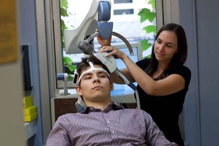 TSM para parar de fumar com estímulos magnéticos. Técnica ajusta equipamento de tratamento na cabeça de paciente.